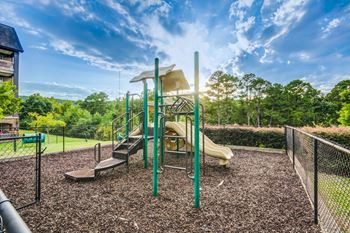 A playground with a yellow slide and a green pole.